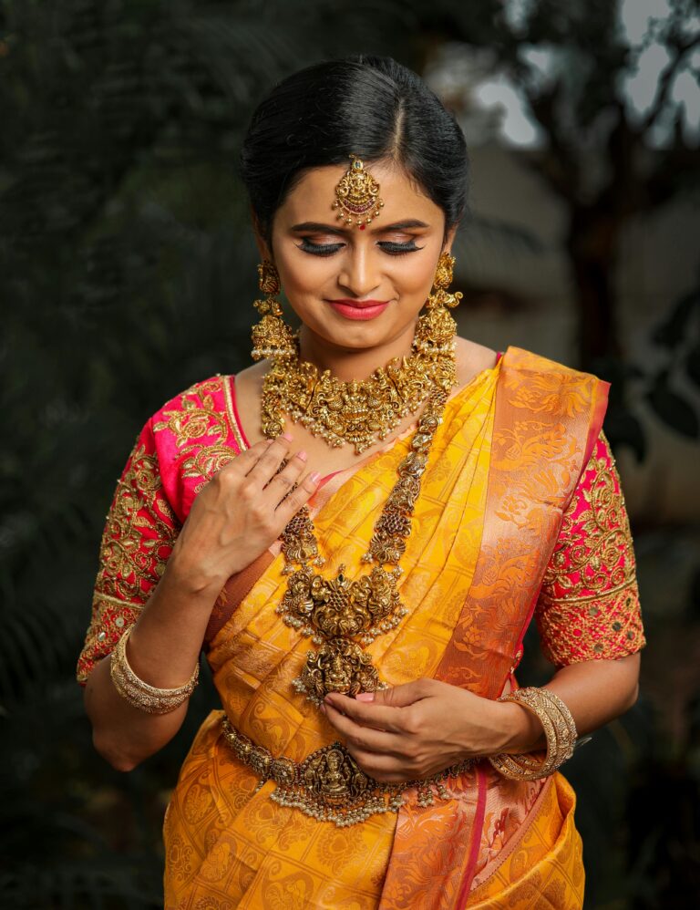 A smiling Indian bride in traditional attire with ornate gold jewelry, captured in a vibrant, colorful setting.